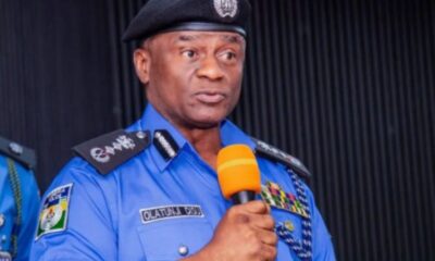 Police officer in a blue uniform speaks into an orange microphone at a podium during a formal event.