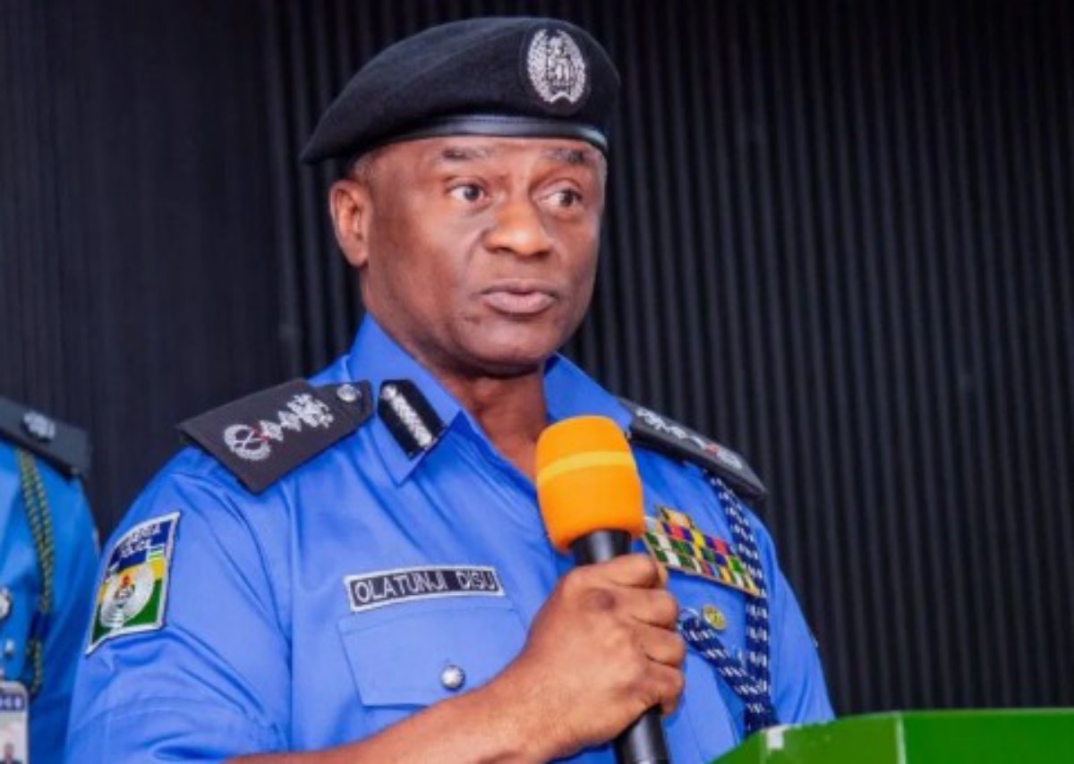 Police officer in a blue uniform speaks into an orange microphone at a podium during a formal event.