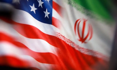 Close-up of a waving American flag blended with the Iranian flag, showing stars and red stripes.