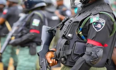 Armored police officer in tactical vest and helmet, holding a rifle.