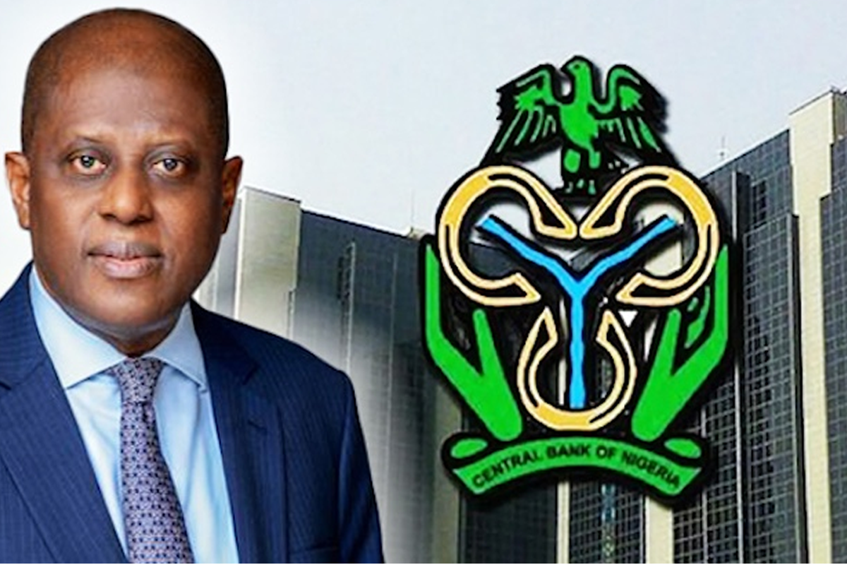 Man in a blue suit stands next to the Central Bank of Nigeria logo on a tall building in the background.