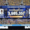 Large stadium scoreboard announcing FIFA World Cup 2026 with world record attendance 3,605,357 and cheering yellow-clad fans in New York/New Jerseye