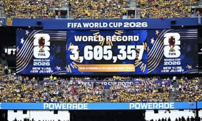 Large stadium scoreboard announcing FIFA World Cup 2026 with world record attendance 3,605,357 and cheering yellow-clad fans in New York/New Jerseye