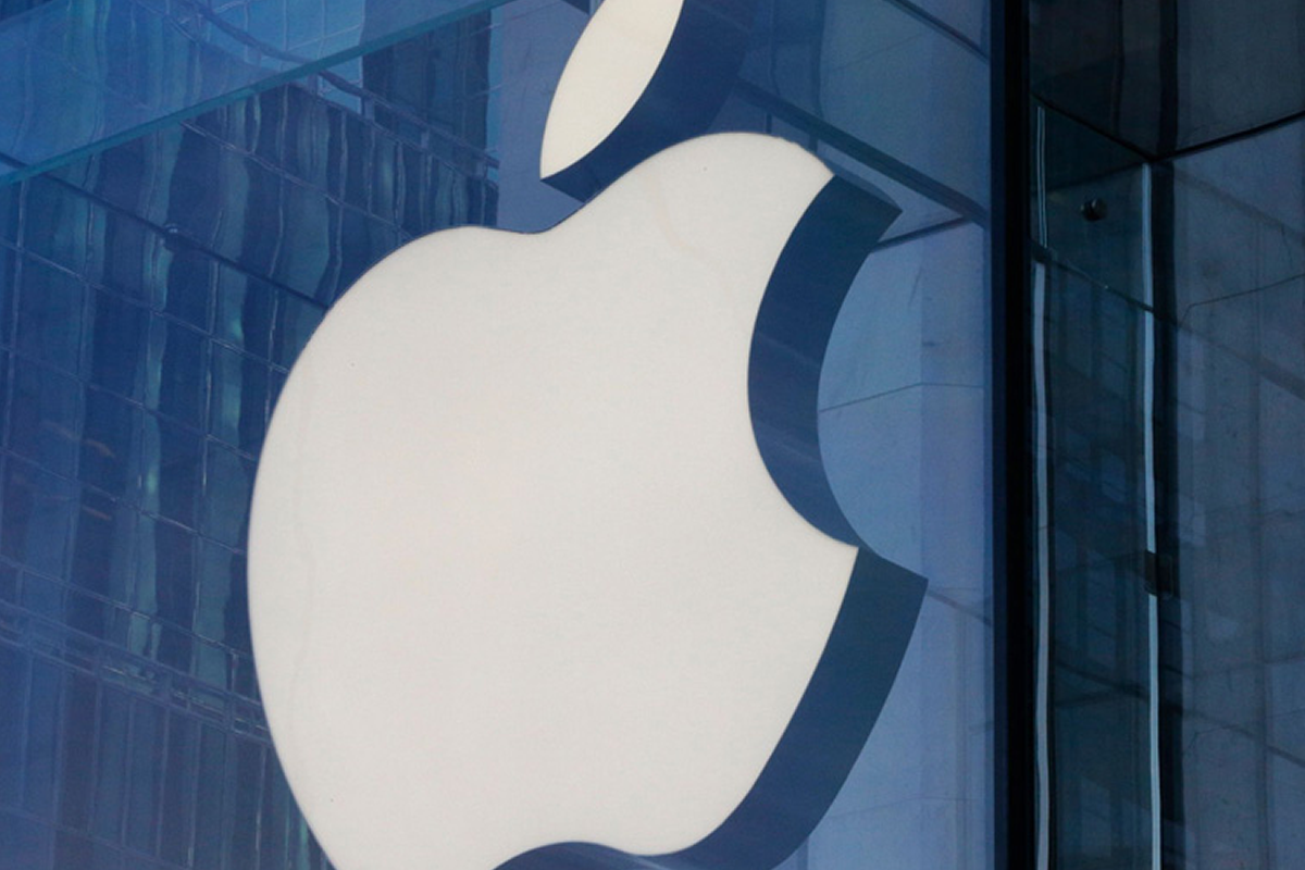 Large white Apple logo mounted on a blue-tinted glass building façade.