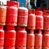 Row of red propane gas cylinders stacked in an outdoor industrial area
