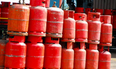 Row of red propane gas cylinders stacked in an outdoor industrial area
