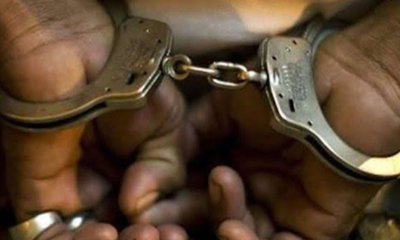 Close-up of hands in metal handcuffs being linked/unlinked, showing chain between cuffs from a close angle, bare fingers visible