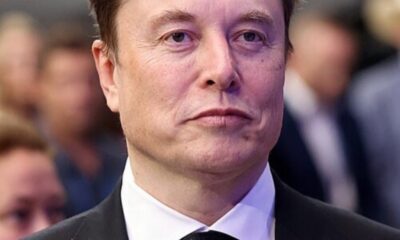 Man in a black suit and white shirt at a formal event, looking straight ahead.