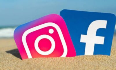 Instagram and Facebook logos partially buried in sand at the beach