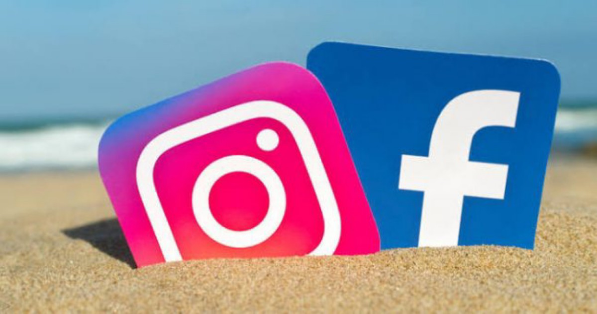 Instagram and Facebook logos partially buried in sand at the beach