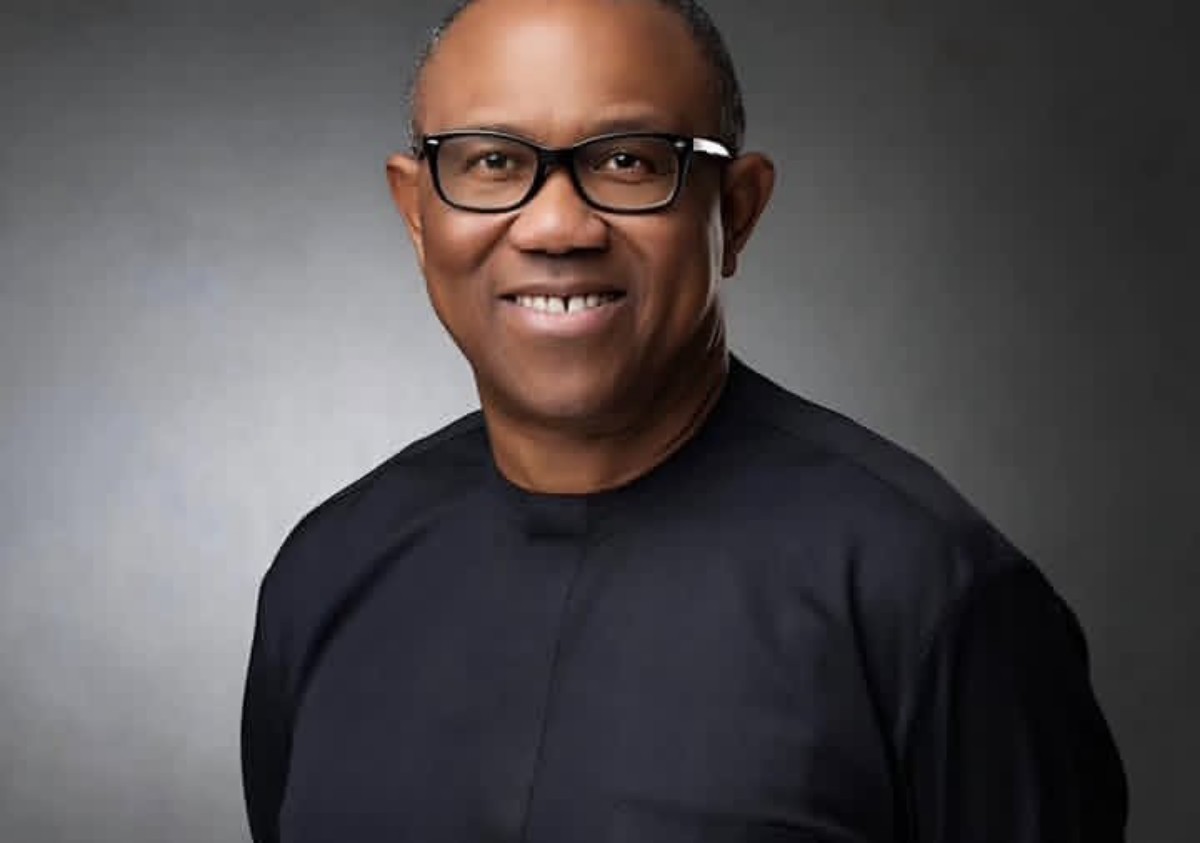 Smiling African American man wearing black-framed glasses and a dark top, against a gray studio backdrop.