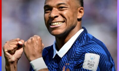 Soccer player in a blue striped jersey celebrating with fists clenched and a smile on his face.