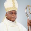 Catholic bishop in white vestments wearing a mitre and holding a silver crozier (staff).