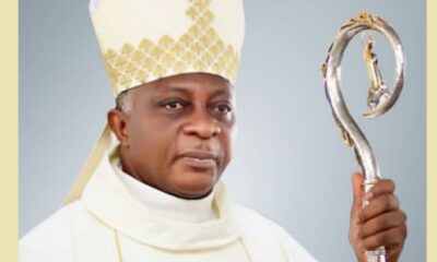 Catholic bishop in white vestments wearing a mitre and holding a silver crozier (staff).