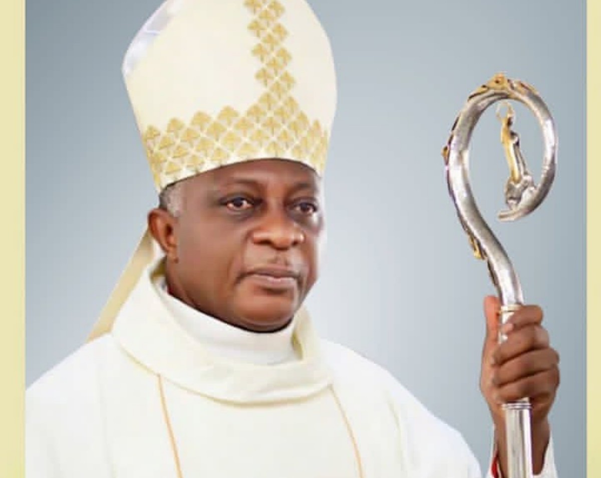 Catholic bishop in white vestments wearing a mitre and holding a silver crozier (staff).