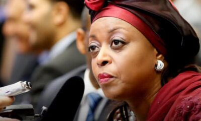 Woman in a red headwrap being interviewed, microphone held up to her lips at a press event
