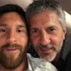 Two men close together taking a selfie, smiling at the camera in a casual setting with one man having a beard and the other gray hair.