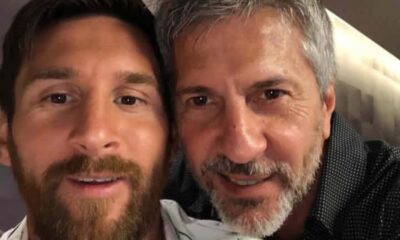 Two men close together taking a selfie, smiling at the camera in a casual setting with one man having a beard and the other gray hair.