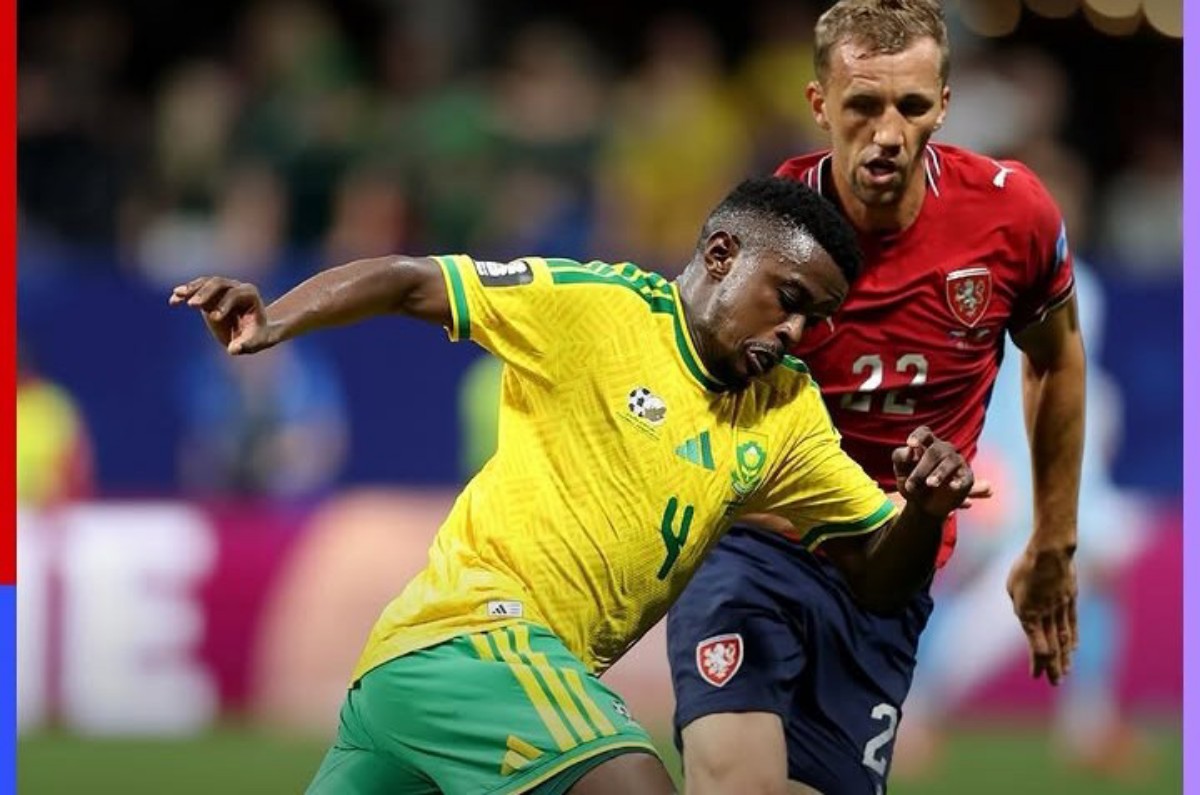 Two soccer players clash for the ball during a match: one in a yellow Brazil kit, the other in red (Wales) kit, in a blurred stadium background.