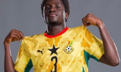 Soccer player wearing a yellow Ghana national team jersey with number 3, lifting the shirt collar in a posing shot.