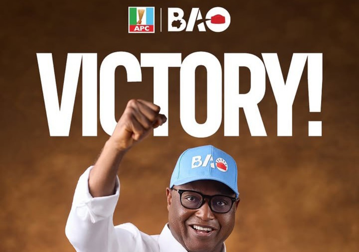 Smiling man in glasses and a light-blue cap raises a clenched fist with a large 'VICTORY!' headline behind him; APC and BAO logos appear at the top, suggesting a celebration poster.