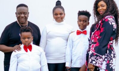 A family of five posing for a formal portrait: two adults and three children, all dressed in white shirts; two boys wear red bow ties, the girl in a white turtleneck, and the mom wears a floral dress.