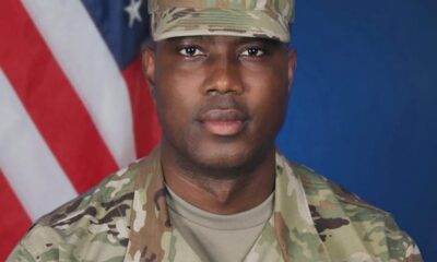 Portrait of a U.S. Army soldier in camouflage uniform with an American flag backdrop in the background.
