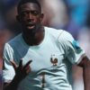 French footballer in a light blue jersey with a rooster crest, signaling with his right hand during a match