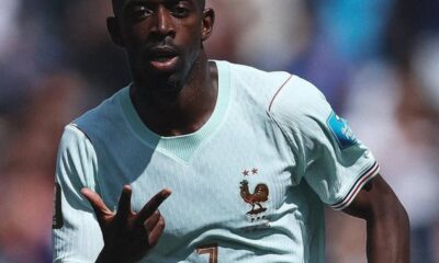 French footballer in a light blue jersey with a rooster crest, signaling with his right hand during a match