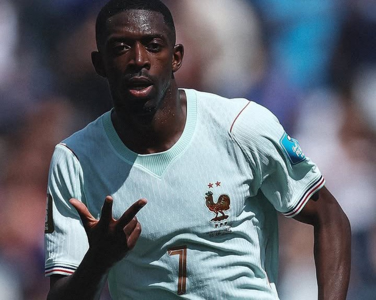 French footballer in a light blue jersey with a rooster crest, signaling with his right hand during a match