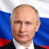Close-up portrait of a mature man in a dark suit with a white shirt, Russia's flag in the background.
