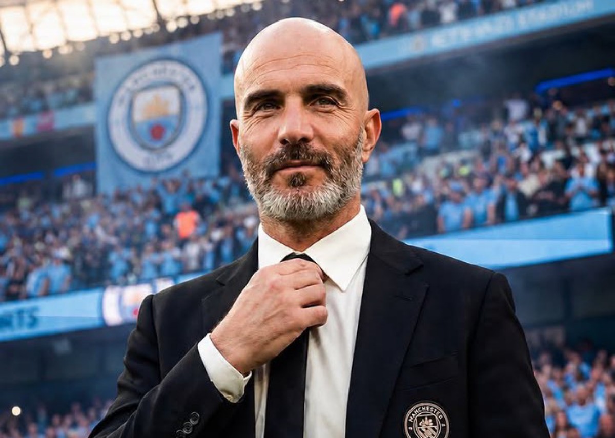 Man in a black suit adjusts his white tie in a stadium packed with blue-clad fans, Manchester City crest on his blazer visible?