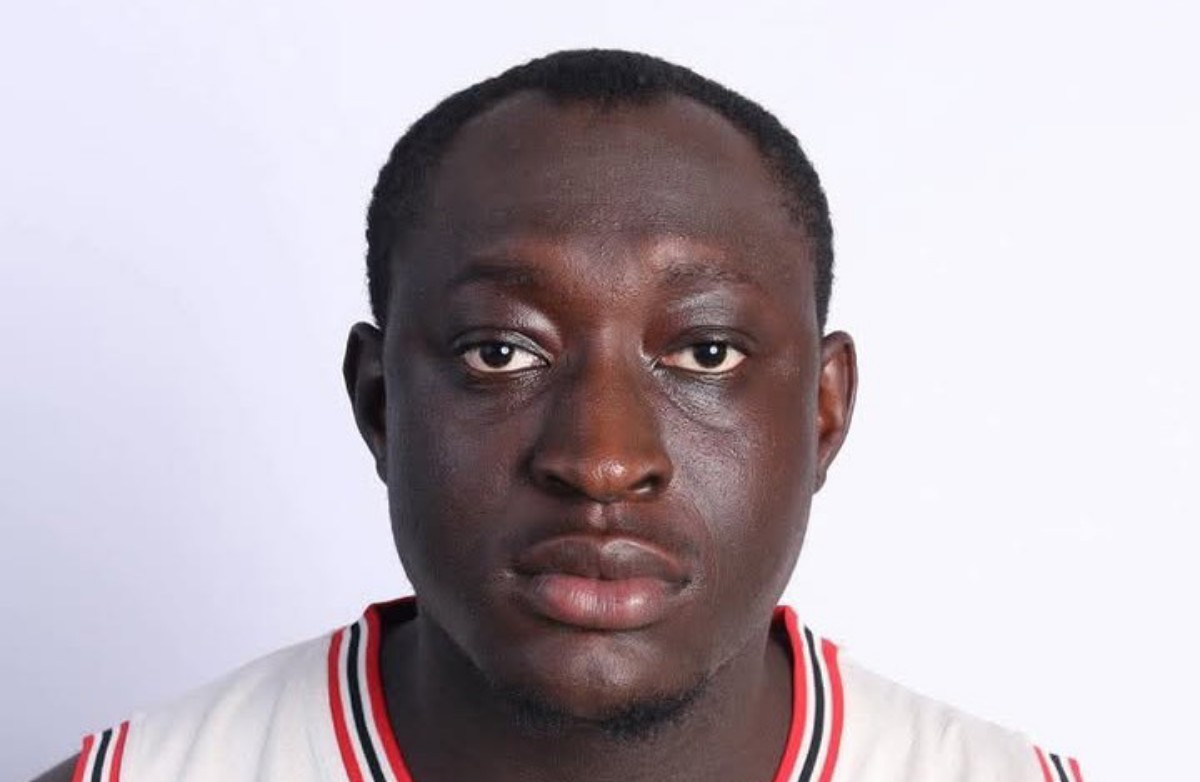 Close-up portrait of a man with a neutral expression, wearing a white jersey with red/black trim against a white background