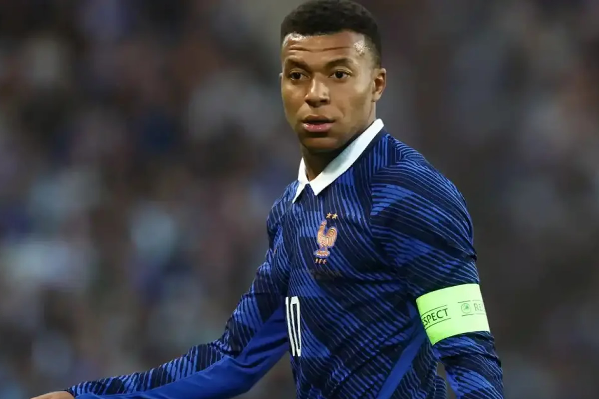 Professional soccer player in a blue France jersey with white collar, wearing a neon captain's armband during a match.
