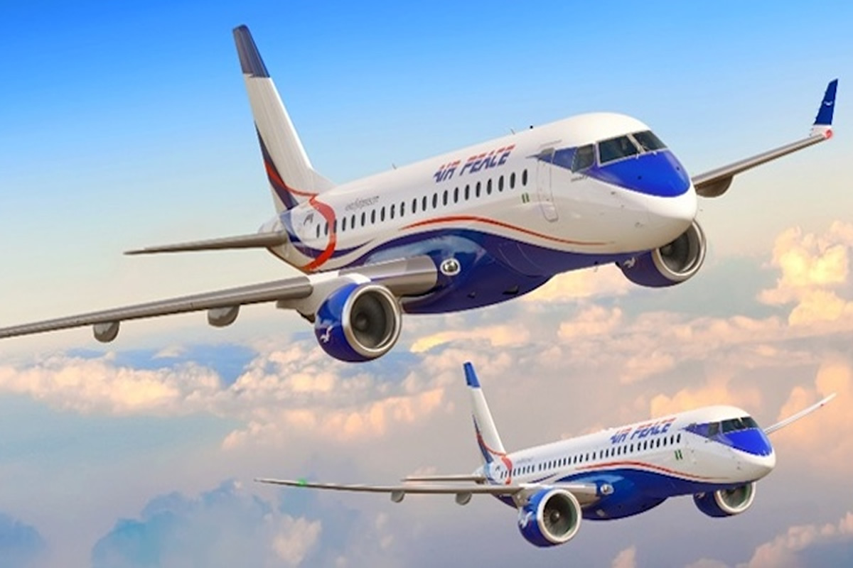Two Air Peace passenger jets in white and blue livery flying above fluffy clouds in a clear sky.