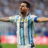 Argentine soccer player with arms outstretched celebrating on the field in a white and light-blue striped jersey with number 10, captain’s armband visible on the sleeve