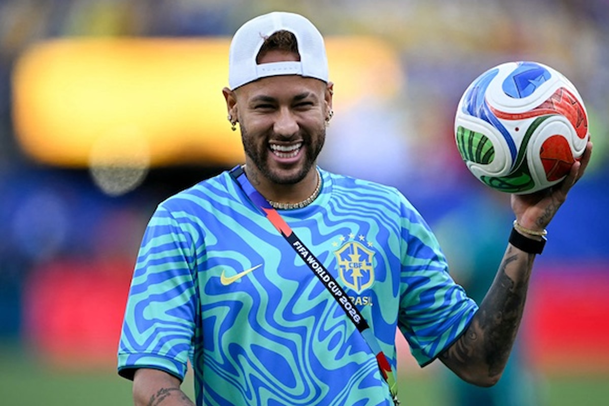 Brazilian footballer in a blue Brazil training jersey holding a colorful soccer ball, smiling on a field.