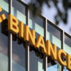 Close-up of a glass building facade with large yellow 3D letters spelling 'FINANCE' along the windows.