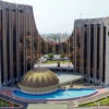 Large symmetrical government-style building with two tall wings, a central dome, and a curved reflecting pool in front.