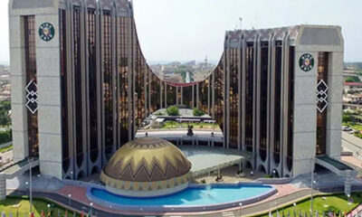 Large symmetrical government-style building with two tall wings, a central dome, and a curved reflecting pool in front.