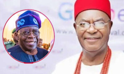 Man in white attire with red cap and beaded necklace smiles at camera; inset shows another smiling man in blue traditional hat.