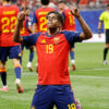 Soccer player in red Spain jersey #19 celebrating on the field with arms raised