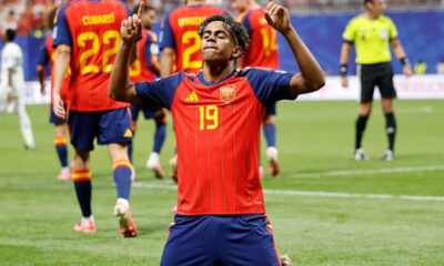 Soccer player in red Spain jersey #19 celebrating on the field with arms raised