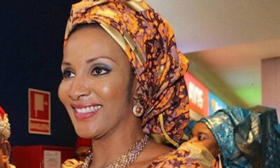 Smiling woman wearing a bright orange and purple headwrap with matching outfit and jewelry in an indoor event setting