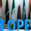 Blue OPEC sign in front of international flags, indicating an energy or international relations setting.