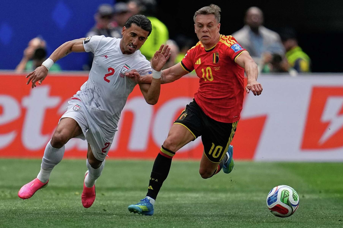 Two soccer players sprint for the ball during a match: a white-jersey defender (number 2) from one team and a red-jersey attacker (number 10) from the opposing team close behind.