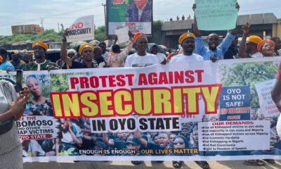 Protestors hold a large banner reading 'Protest Against Insecurity in Oyo State' with people behind and signs demanding end to insecurity, outdoors