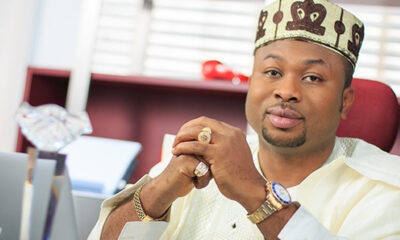 Man wearing traditional Nigerian attire and cap sits at a desk with hands clasped