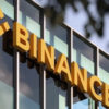Bold yellow letters spelling FINANCE mounted on a glass-fronted office building.