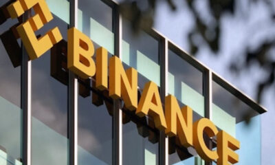 Bold yellow letters spelling FINANCE mounted on a glass-fronted office building.